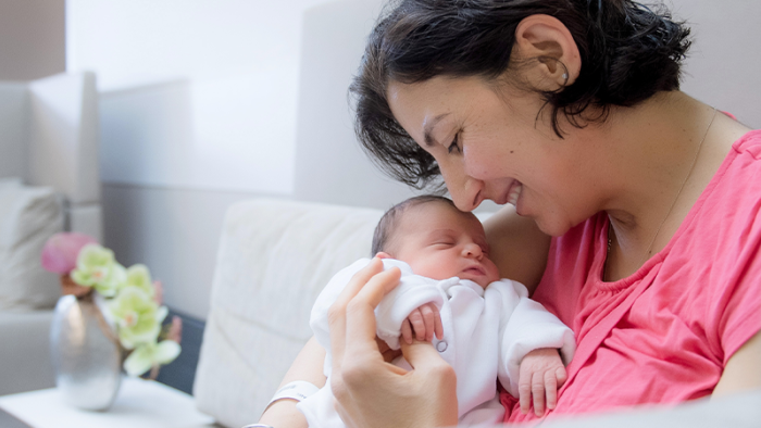 Pregnant woman lovingly holding her baby and smiling